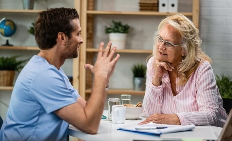 A friendly caregiver talking with a smiling elderly woman during a home care visit representing personalized and compassionate home care in Pennsylvania.