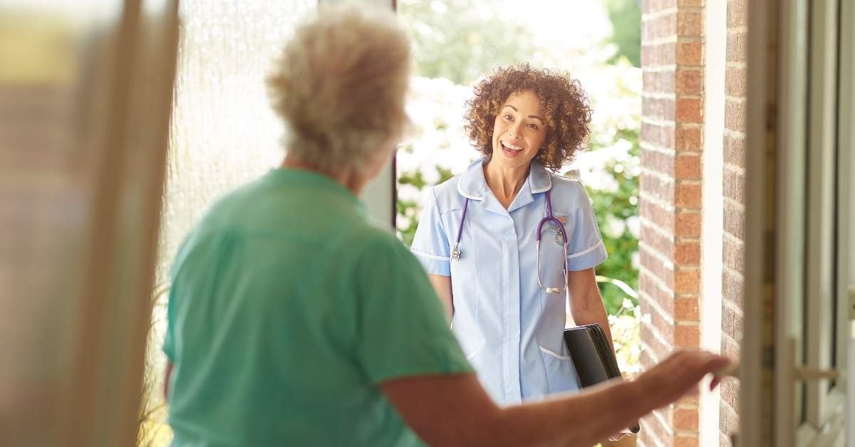 Smiling home health nurse visiting an elderly woman at her home, representing the difference between home care and home health care.