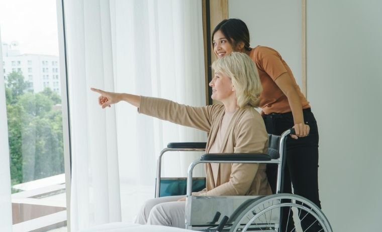 Caregiver providing compassionate assistance to a senior woman in a wheelchair at home showcasing personalized support and companionship as part of non-medical home care PA services.
