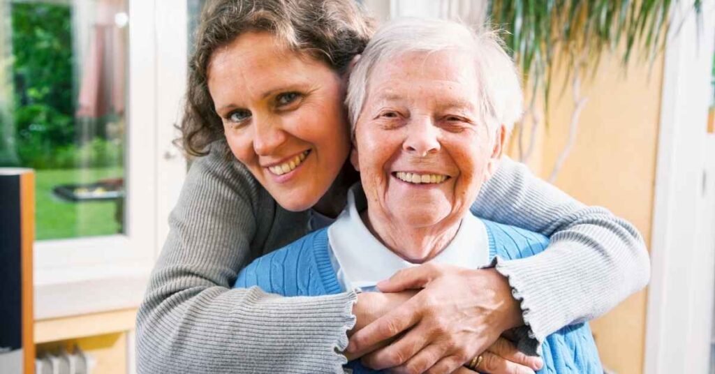 Family caregiver smiling while supporting an elderly parent at home, showing compassionate in-home support for rural vs urban home care in Pennsylvania.